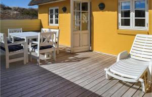 a deck with a table and chairs and a yellow house at Holiday Home Rauhesvej Hvide Sande in Bjerregård +22 photos