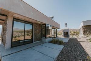 a house with glass doors and a view of the desert at Sunset de los Andes Lodge in Ciudad Lujan de Cuyo
