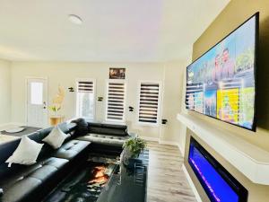 a living room with a black leather couch and a flat screen tv at Edmonton Family Luxury Home AirHoky,PooLTable 14 Min Airport and Edmonton South, Party or Events Strictly Restricted in Nisku