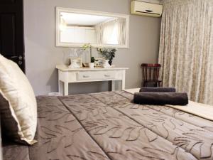 a bedroom with a bed with a table and a mirror at The Bethel House in KwaDabeka