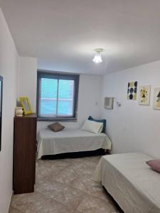 a bedroom with two beds and a window at Apartamento 2 quartos - Em frente a praia in Saquarema