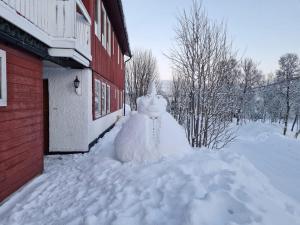 Un muñeco de nieve sentado afuera de un edificio en la nieve. en Nydelig hybelleilighet nært sentrum, en Tromsø