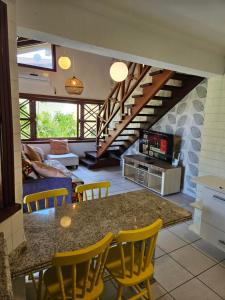 a kitchen with a table and chairs and a living room at Condomínio Canto do Mar a 50 Metros Praia de Maresias in Maresias