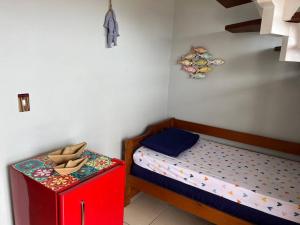 a small bedroom with a small bed and a red cabinet at Linda cobertura duplex frente pro mar. in Arraial do Cabo