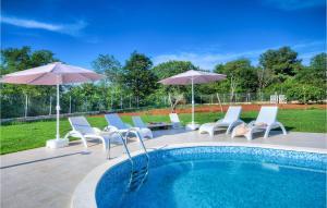a pool with chairs and umbrellas on a patio at Villa Lemaliante in Umag