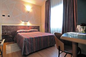 フィオラーノ・モデネーゼにあるHotel Alexanderのベッドとデスクが備わるホテルルームです。