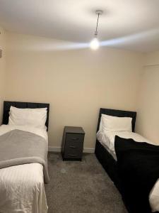 a bedroom with two beds and a nightstand between them at Spacious City Centre Home Near Hospital & M5 in Worcester