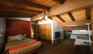 a bedroom with two beds and a tv and wooden ceilings at Donner Lake Gem 4Br 3Bath Chalet in Truckee