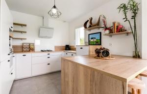 kuchnia z białymi szafkami i drewnianym stołem w obiekcie Cozy Home In Lyons-La-Forêt w mieście Lyons-la-Forêt