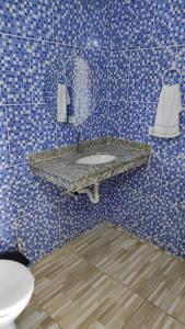 a blue tiled bathroom with a sink and a toilet at Hostel Vista Mar in Porto Seguro