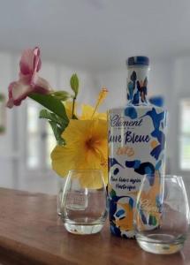a bottle of water and a vase with flowers in it at Haut de villa 1chambre climatisée à 3min de l'habitation Clément in Le François