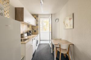 Una cocina con gabinetes blancos y una mesa y sillas. en Centrally located 2-room apartment, en Hannover