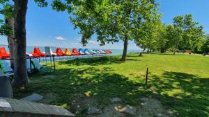 einen Park mit Stühlen, Bäumen und Wasser in der Unterkunft Apartments in Zamardi - Balaton 52987 in Zamárdi
