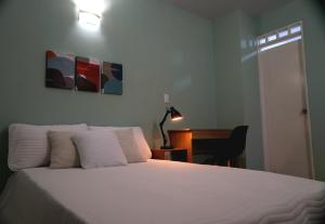 a bedroom with a white bed with a desk and a lamp at Ideal para trabajar y descansar in Cali