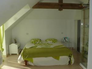 Un dormitorio con una cama con sábanas verdes y una ventana en La Grouas, en Vauchrétien