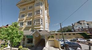 a large yellow building with cars parked in a parking lot at Apartamento Solar do Centro - Gramado RS in Gramado