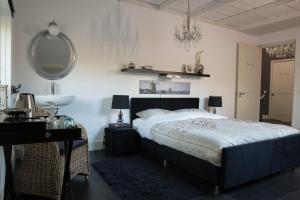 1 dormitorio con cama, escritorio y espejo en B&B Van Hunebed Naar Jullie Bed en Schoonoord