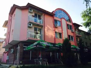 a large building with an umbrella in front of it at Family Hotel Relax in Strelcha