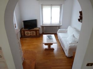 ボルカ・ディ・カドーレにあるAppartamento Soleのリビングルーム(白いソファ、コーヒーテーブル付)