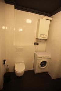 a small bathroom with a toilet and a washing machine at Apartament Prusa in Szczawno-Zdrój