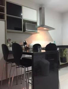 une cuisine avec un comptoir noir et des tabourets dans l'établissement Casa ao lado Pedreira Paulo Leminski confortável 15 min centro da cidade e centro histórico pontos turísticos shows eventos fácil acesso com estacionamento, à Curitiba