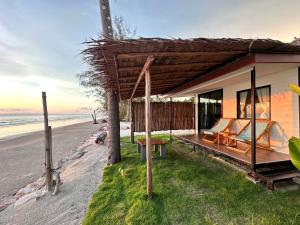 a house on the beach with a porch and chairs at The hi Ocean resort เดอะไฮโอเชี่ยนรีสอร์ต in Khlong Yai