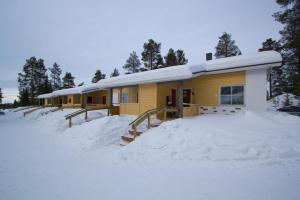 ein gelbes Haus mit Schnee davor in der Unterkunft Polar Star Apartments in Levi