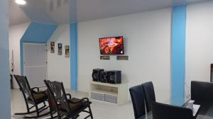 a waiting room with chairs and a table and a tv at Cabaña Rochy in Coveñas