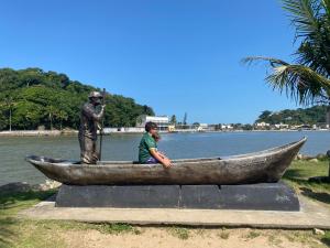 a woman sitting in a boat next to a statue at Pousada Amarela Beach in Itanhaém