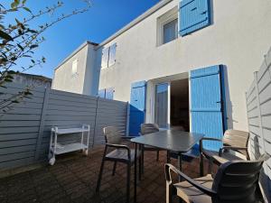 a patio with a table and chairs in front of a building at Maisonette Ensoleillée Proche Plage à La Faute-sur-Mer – 4 Pers, Animaux Sur Demande - FR-1-476-21 in La Faute-sur-Mer