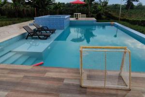 a swimming pool with two chairs and a net in it at Finca en el Quindío - Arrullo Cafetero in Quimbaya