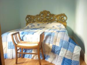 a bed with a blue and white quilt and a wooden chair at San Zanobi Apartment in Florence
