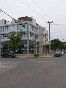 a large white building with cars parked in front of it at Eneas Flat luminoso con cochera in Pinamar