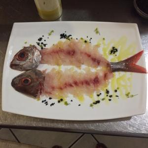 un piatto di cibo con un pesce sopra. di Hotel Mezzatorre a Ventotene