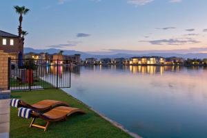 a bench sitting on the grass next to a body of water at Armonia89- Villa Lago Dream Lakefront Pool Luxury 4BR Oasis in Indio