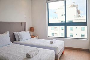 Un dormitorio con dos camas y una gran ventana. en Dizztravel Apart Murano Centro Exclusivo apto 2701, en Cartagena de Indias