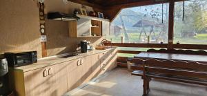 a kitchen with a counter and a bench and a window at Căsuțe Zăvoi Bulz in Bulz