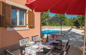 stół z czerwonym parasolem i basenem w obiekcie Lovely Home In Rovinj w Rovinj