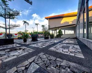 a stone courtyard with a building and palm trees at Prima SR Hotel & Convention Yogyakarta in Yogyakarta