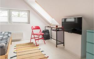 a living room with a tv and a red chair at Lovely Home In Taszów With Sauna in Taszów