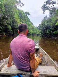 a man sitting in a boat on a river at IGUANA HAUS IQUITOS in Iquitos