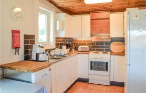 a kitchen with white appliances and a wooden ceiling at 3 Bedroom Awesome Home In Mariefred in Mariefred