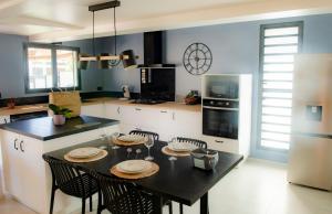 a kitchen with a table with chairs and a refrigerator at A l'ombre du letchi in Saint-Paul