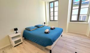 a bedroom with a blue bed in a room with windows at Appartement Cœur de ville in Jonzac