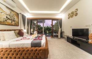 Un dormitorio con una cama grande y un televisor de pantalla plana. en Alsava Villa and Suites Canggu, en Canggu