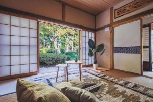 a living room with a couch and a table at 最大8名 庭園に住むアート Active Art Hotel 80畳の広さを誇る古民家 日本庭園を独り占め in Sado