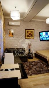 ein Wohnzimmer mit einem Bett und einem Fernseher in der Unterkunft Main Street Apartments in Chişinău