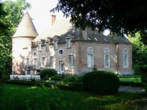 an old brick house with a turret on a lawn at Le Pavillon de l'Orangerie in Meursanges