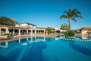 a swimming pool in front of a house with a palm tree at Perdepera Resort in Cardedu