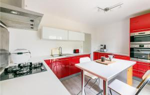 a kitchen with red cabinets and a white table at Gorgeous Home In Joué Les Tours in Joue-les-Tours
